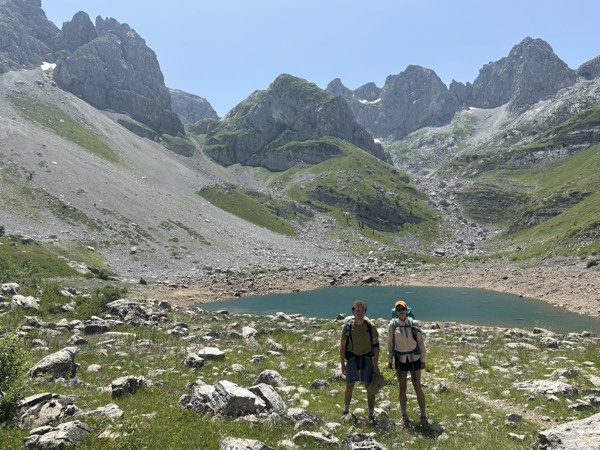 Two hikers in front of an alpine lake