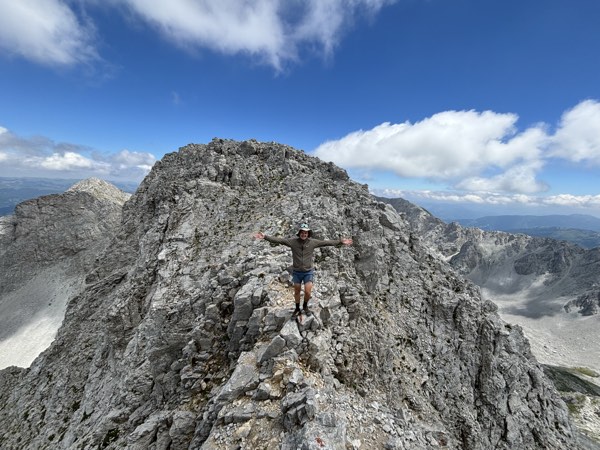Hiker with open arms on a rocky summit ridge