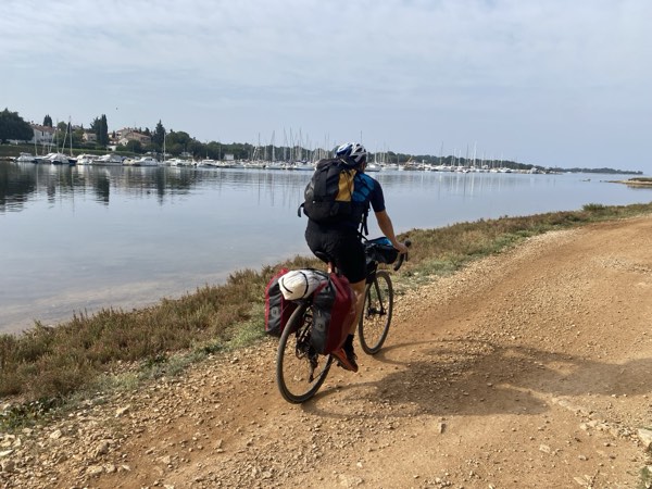 Cyclist with packed bags riding along the seaside